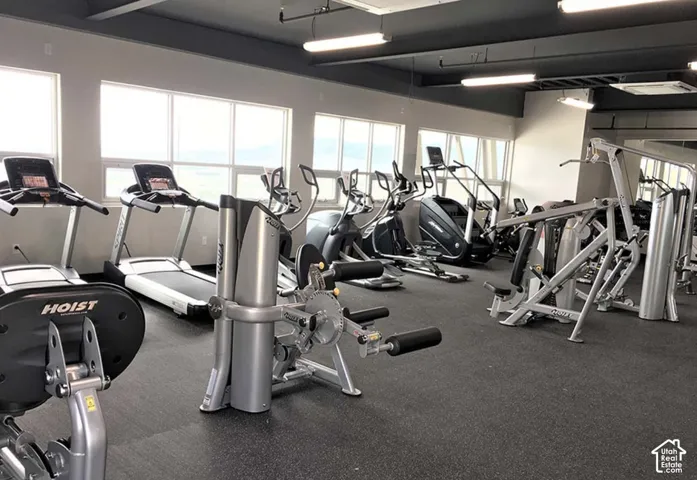 Exercise area featuring rubber flooring, oversized windows, and high-contrast ceilings with integrated linear lighting