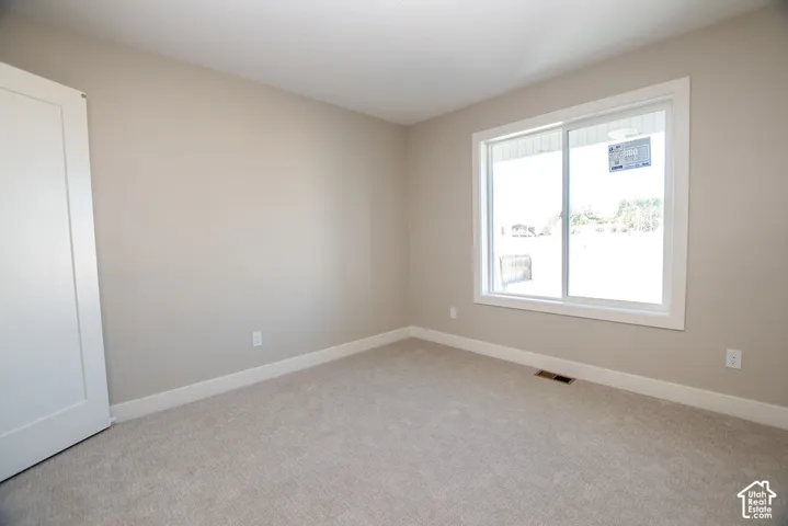 Neutral tone wall paint, white trim, recessed lighting, white interior door, and light-colored carpet flooring