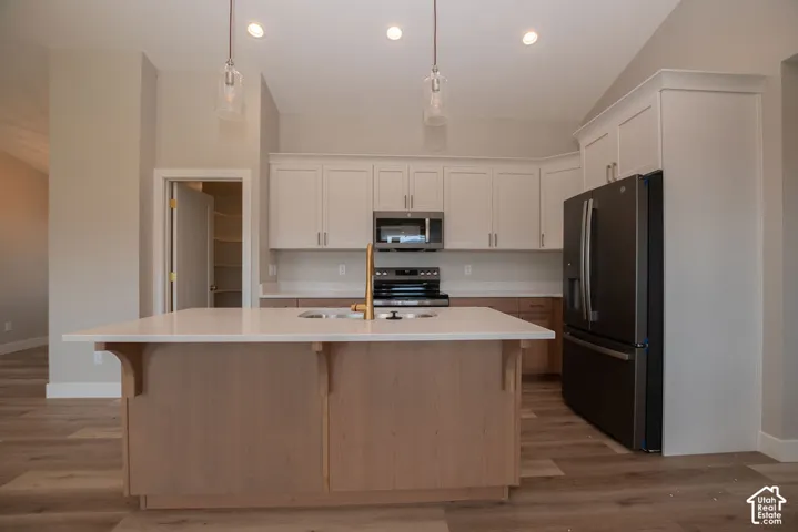 Kitchen featuring a center island with sink, brass-finish faucet, and pendant lighting