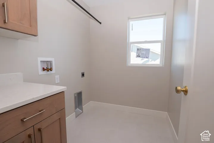 Light wood-finish cabinetry, light-toned countertop, and light-toned flooring in a dedicated utility space