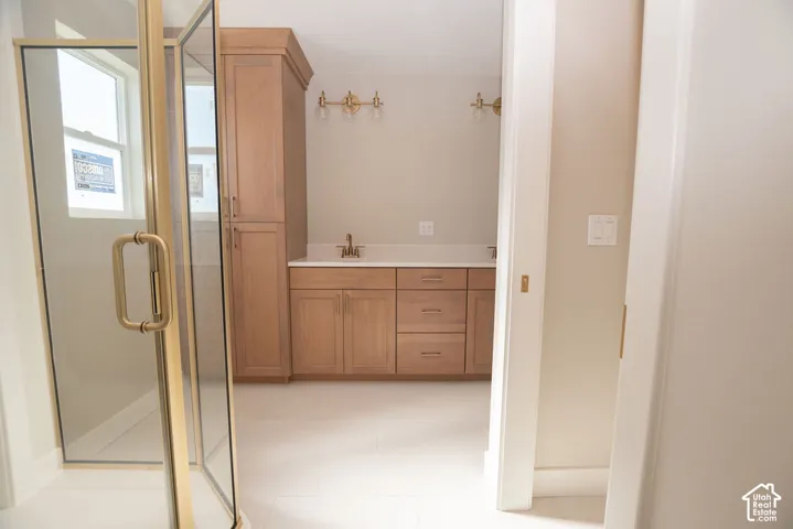 Custom wood cabinetry with an integrated linen tower, white countertop, and gold-finish hardware