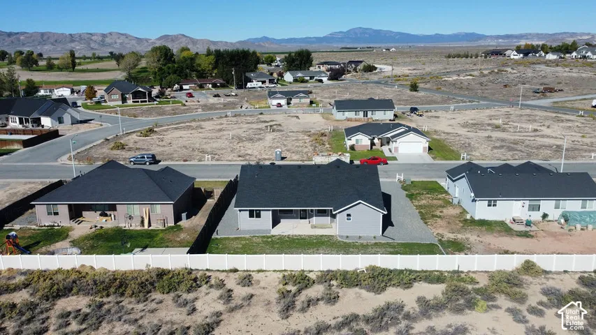Newly constructed residence featuring a dark shingle roof, light gray siding, an attached garage, and a concrete driveway