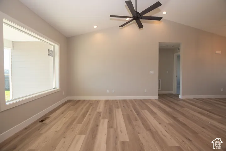 Vaulted ceiling with a ceiling fan, recessed lighting, wood-finish flooring, and white trim