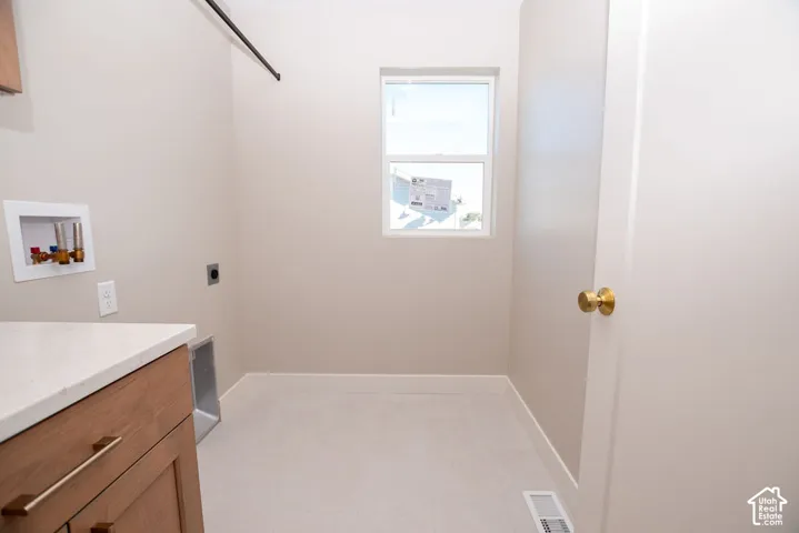 Laundry area featuring a large window, light-toned flooring, built-in cabinetry, and a countertop