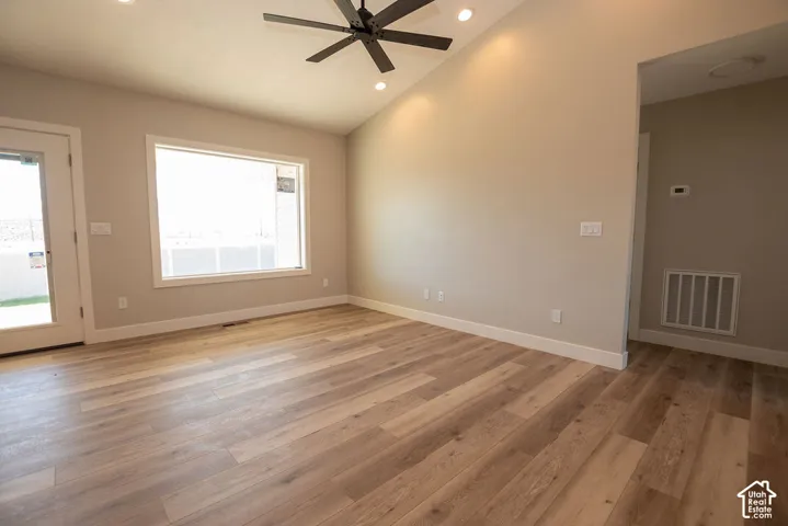 Vaulted ceiling with recessed lighting, black ceiling fan, wood-finish flooring, and a glass-paneled door