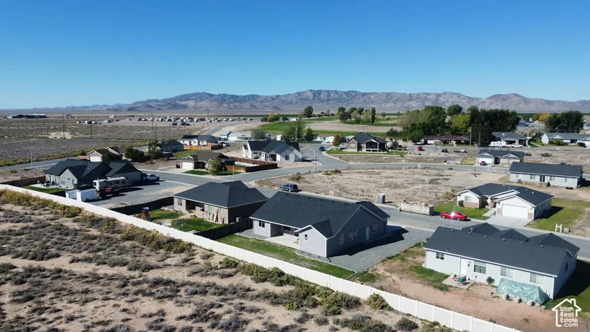 Residential development featuring single-story homes with attached garages, paved roads, and mountain scenery