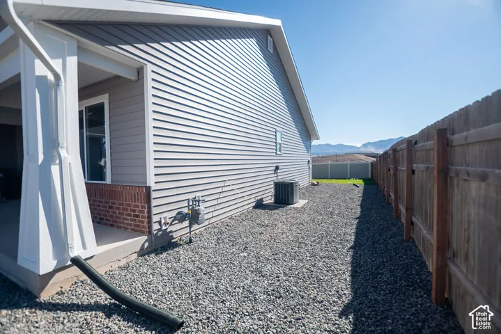 Side yard with gravel landscaping, wood fencing, and a covered patio area
