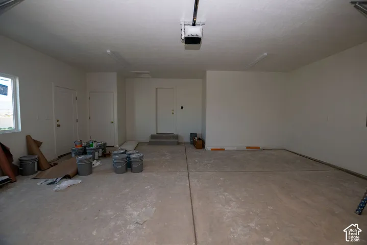 Concrete flooring, multiple access doors, overhead lighting, and an automatic garage door opener