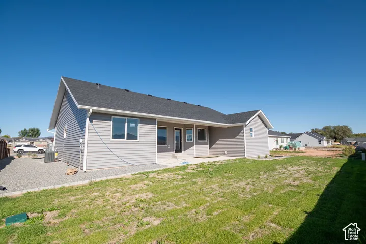 Gray horizontal siding exterior with a dark shingle roof, rear patio, and a gravel perimeter