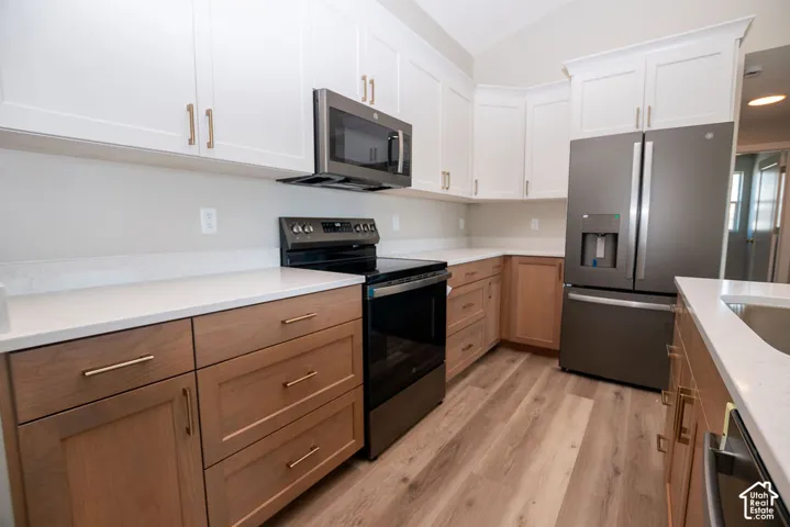 White shaker cabinetry with gold-tone hardware, wood-finish flooring, and white countertops
