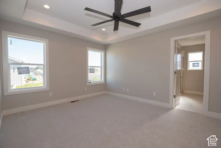 Spacious room featuring a tray ceiling, recessed lighting, and a contemporary ceiling fan