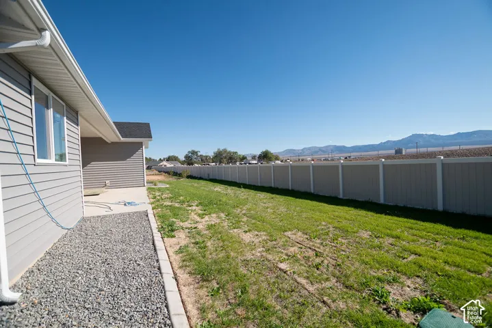 Expansive backyard featuring a partial vinyl fence, a concrete patio, and a gravel perimeter