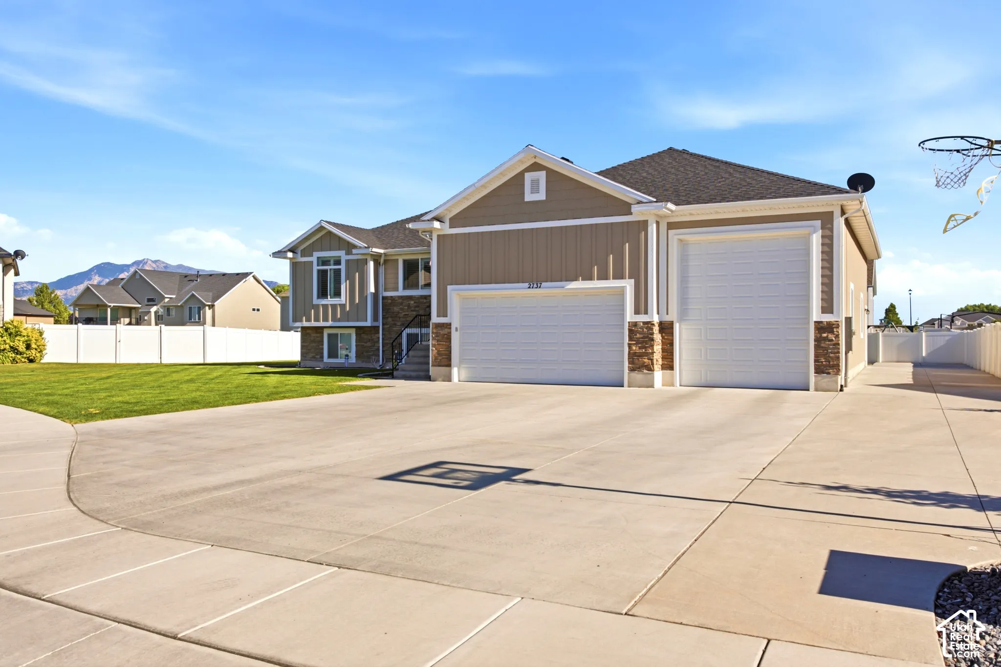 Contemporary residence featuring a two-story design with a split-level entry, a broad concrete driveway, and a spacious green lawn