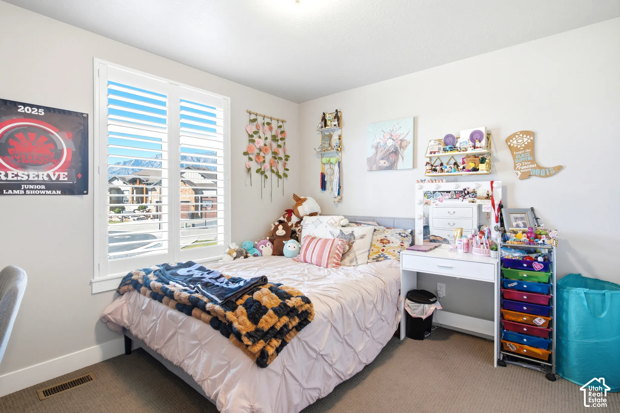 Spacious room featuring a large window with white plantation shutters, neutral-toned walls, and carpet flooring