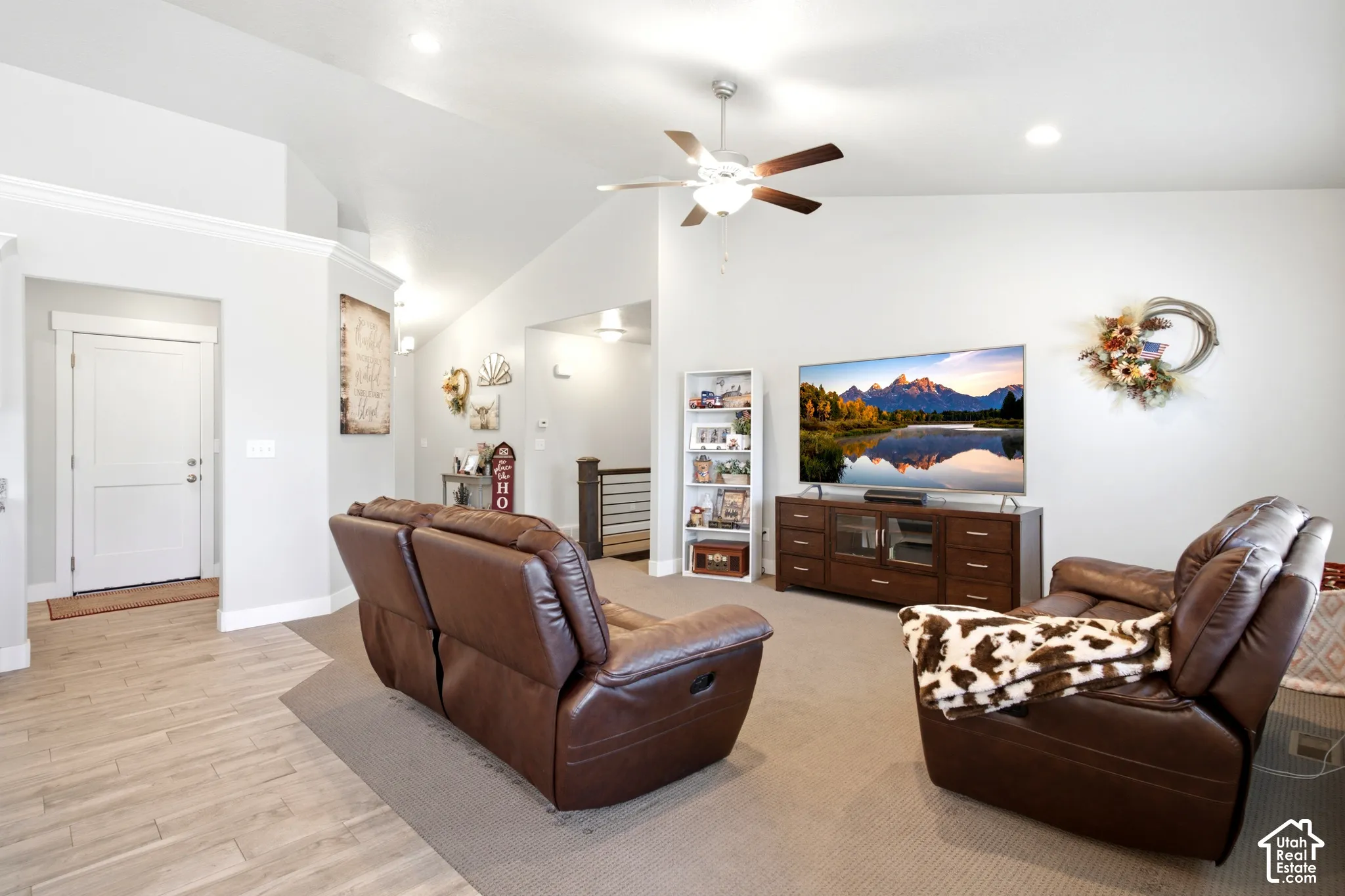 Spacious living area featuring light-toned walls, a vaulted ceiling, and recessed lighting