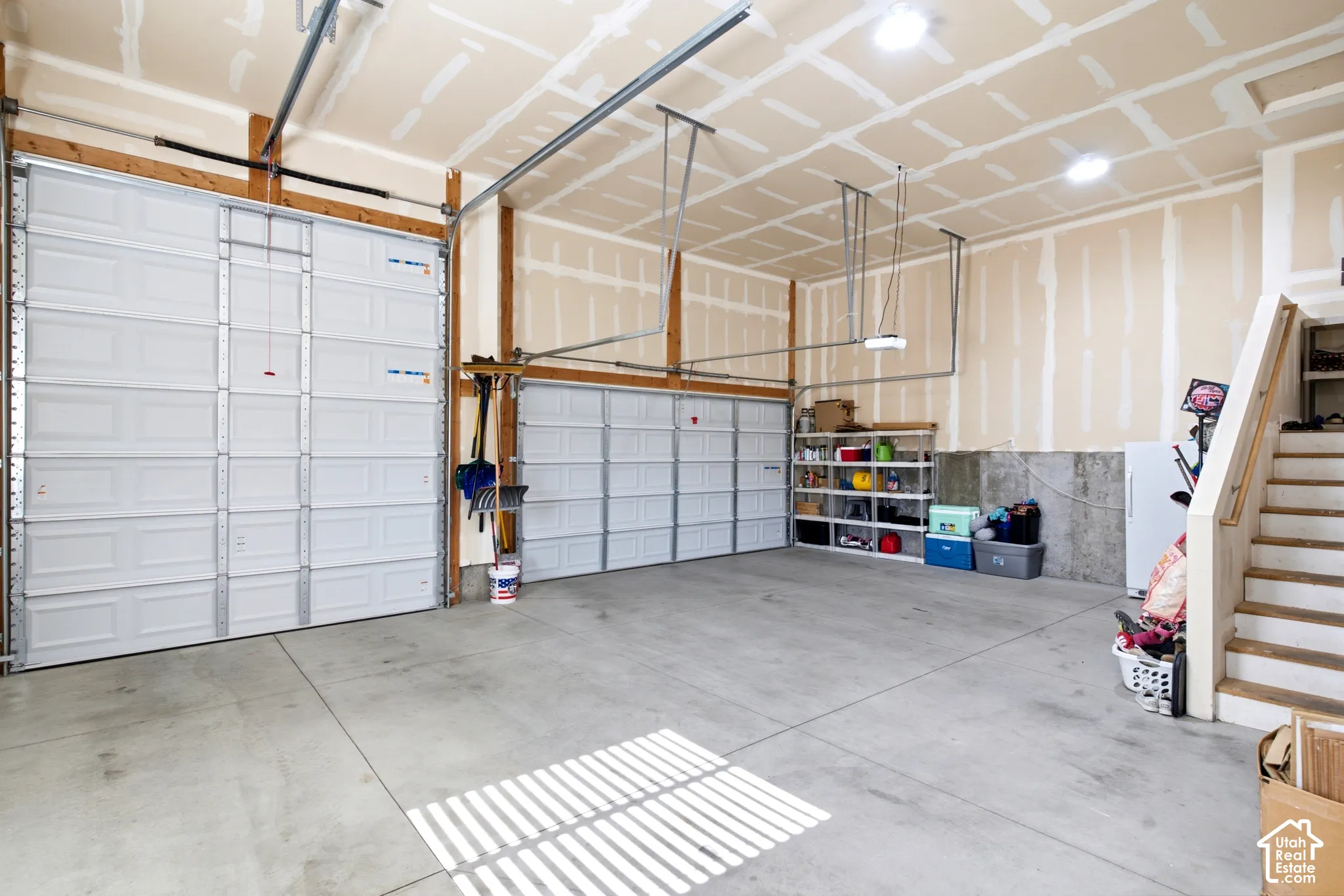 Two overhead garage doors with concrete flooring and exposed wood framing