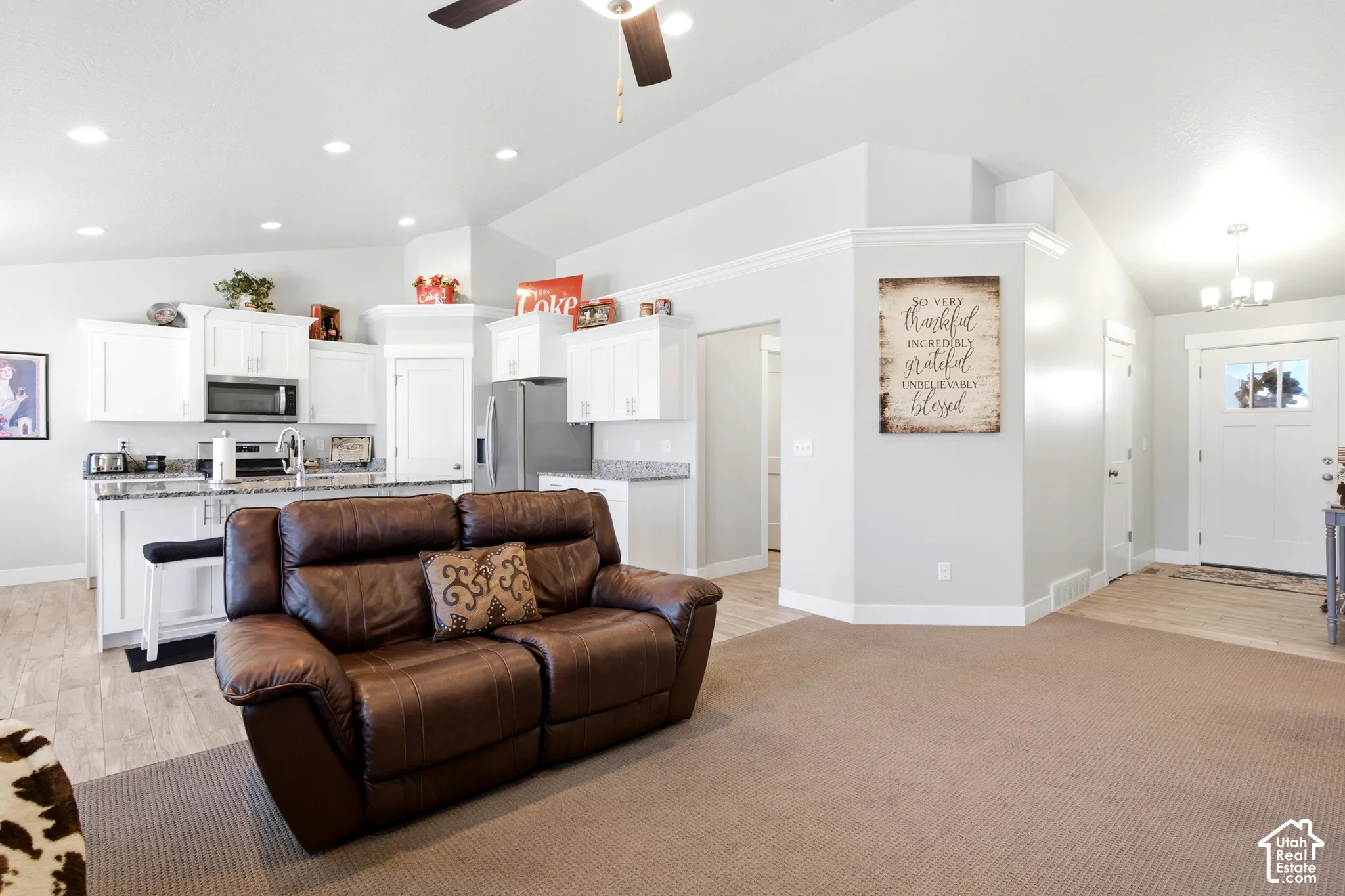 Open-concept living space featuring a kitchen with white cabinetry, stainless steel appliances, and granite countertops