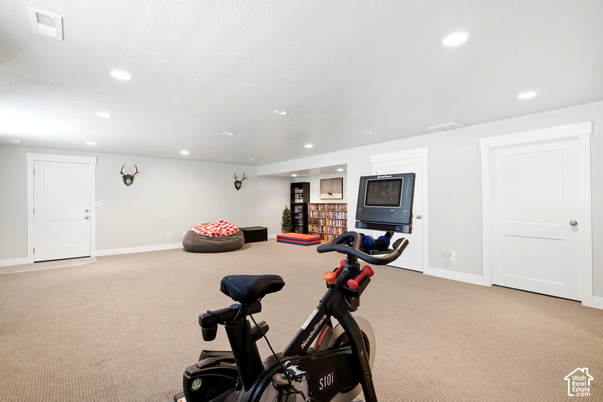 Expansive recreation space featuring light-colored carpeting, recessed ceiling lighting, and white trim