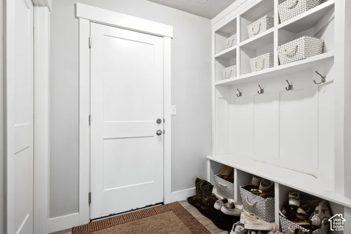Entryway featuring a white paneled door with modern hardware, built-in shelving, and coat hooks