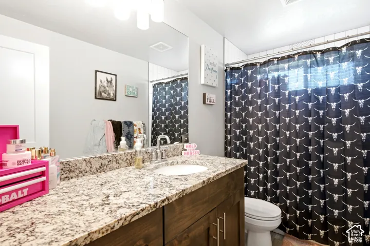 Bathroom featuring a dark wood-finish vanity with ample storage, a speckled stone countertop, and an undermount sink