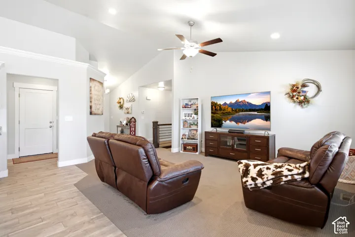 Spacious living area featuring light-toned walls, a vaulted ceiling, and recessed lighting
