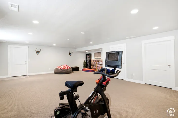 Expansive recreation space featuring light-colored carpeting, recessed ceiling lighting, and white trim