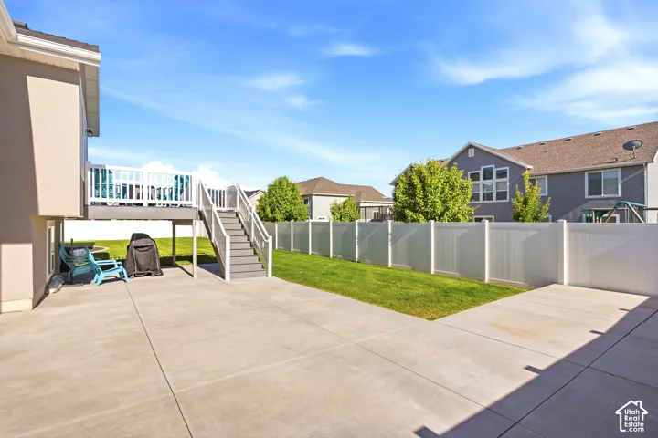 Expansive concrete patio area featuring a raised deck with white railing and stairs