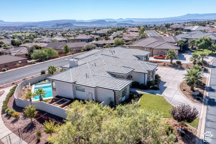 Exterior featuring a tiled roof, stucco siding, stone accents, and a paved driveway