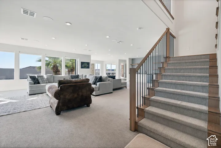 Recessed lighting, wood-finish and metal balusters, carpeted staircase, extensive window array, and neutral wall tones