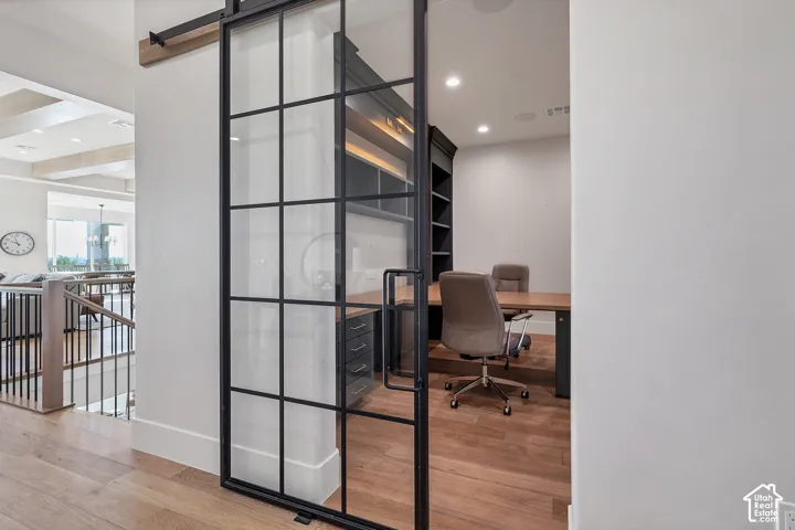 Sliding glass and metal grid door, wood-finish flooring, built-in shelving, and recessed lighting