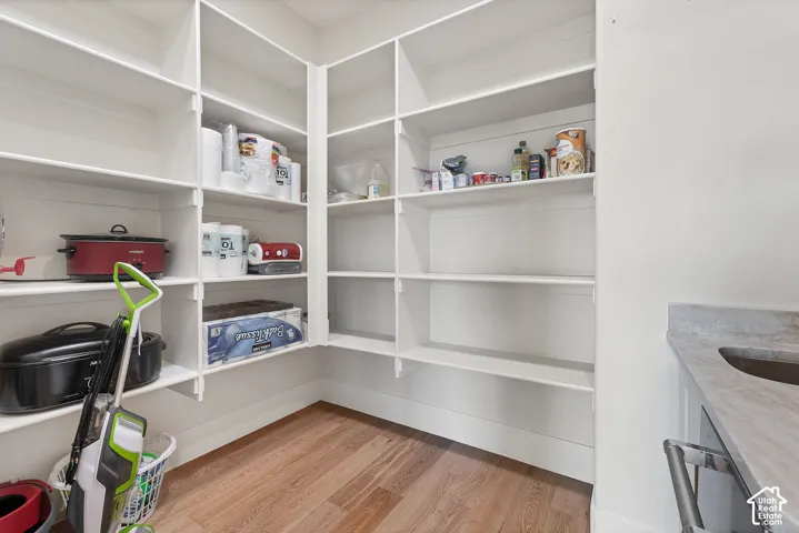 Extensive built-in shelving, wood-finish flooring, white cabinetry, and a countertop with an integrated sink
