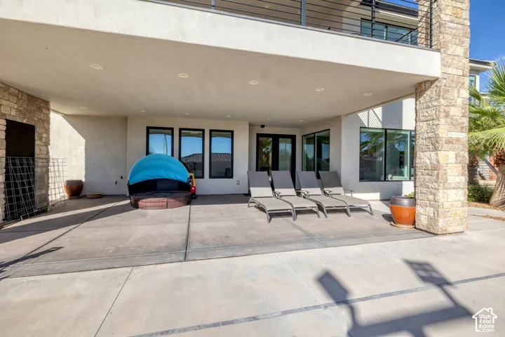 Covered patio with recessed lighting, stone-clad columns, and multiple large windows