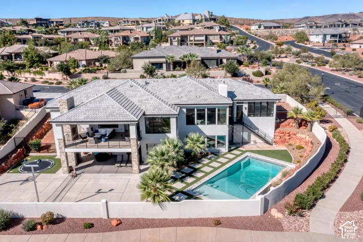 Contemporary residence featuring a multi-level roof, ground-level swimming pool, and an upper-level covered patio