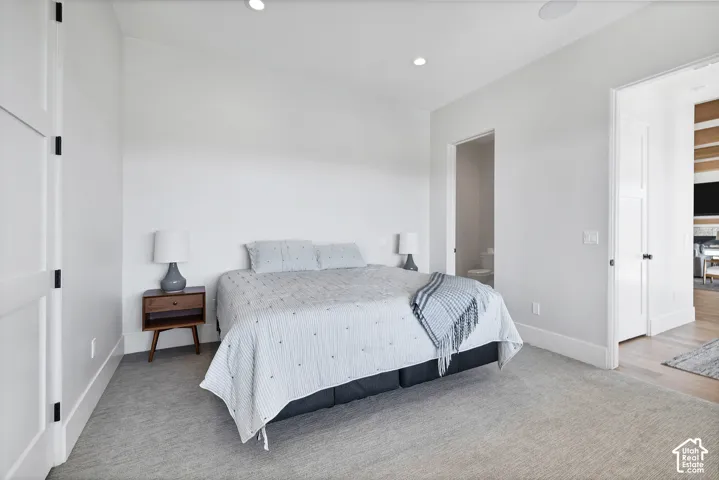 Carpeted flooring extending through the room, recessed ceiling lighting, and a white interior door with black hardware