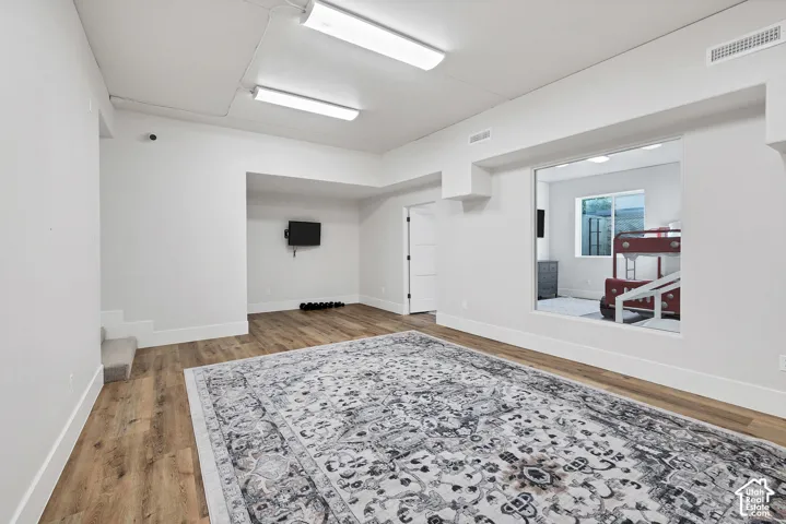 Recessed lighting, wood-finish flooring, white trim, and a window opening to an adjacent room