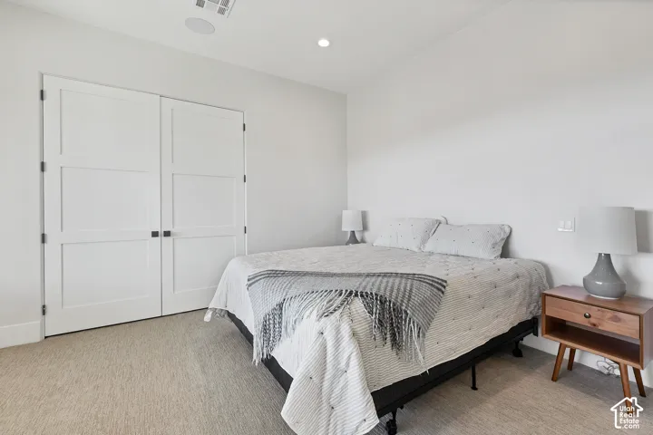 Wall-to-wall carpeting, recessed ceiling lighting, and built-in closet with panel doors and matte black hardware