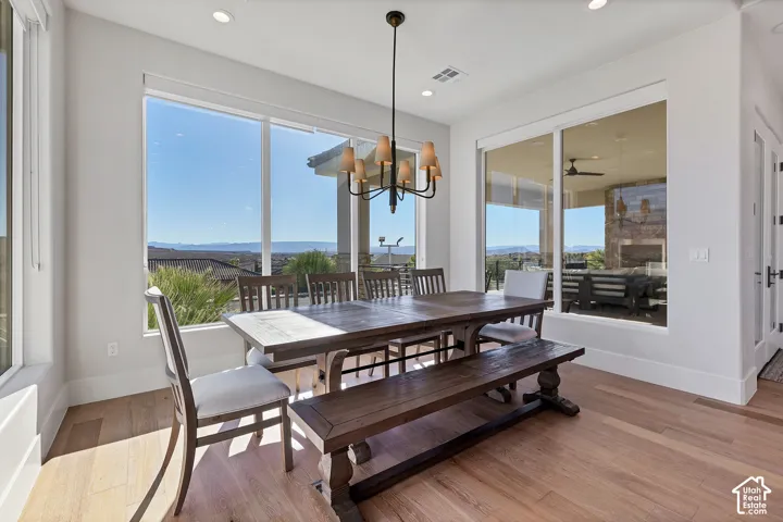 Expansive windows, light wood-finish flooring, recessed lighting, and a modern chandelier