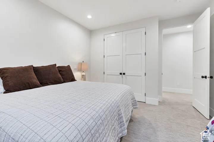 Recessed ceiling lighting, white interior walls, white paneled doors with black hardware, and light-toned carpet flooring