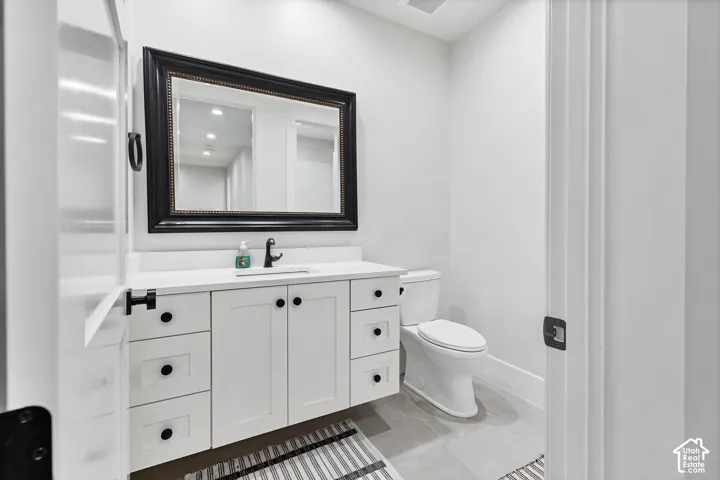 White vanity with a solid surface countertop, undermount sink, and matte black faucet
