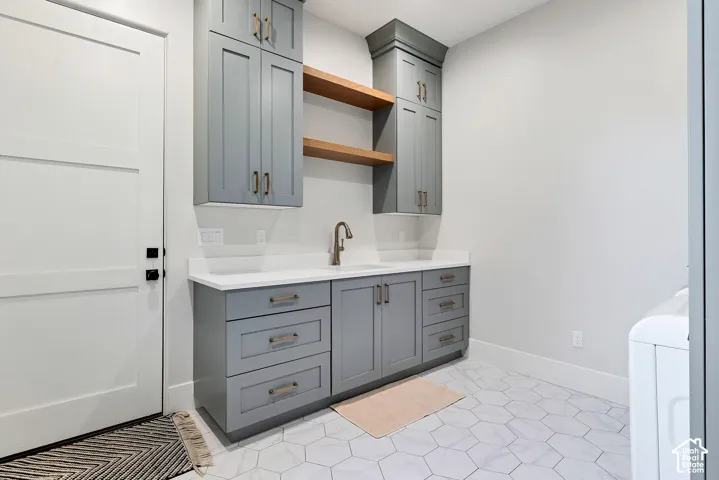 Custom cabinetry with open shelving, integrated sink, stone-finish countertop, and hexagon tile flooring
