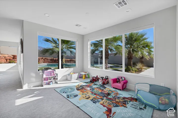 Light gray wall paint, recessed lighting, multiple large windows, and gray textured carpet