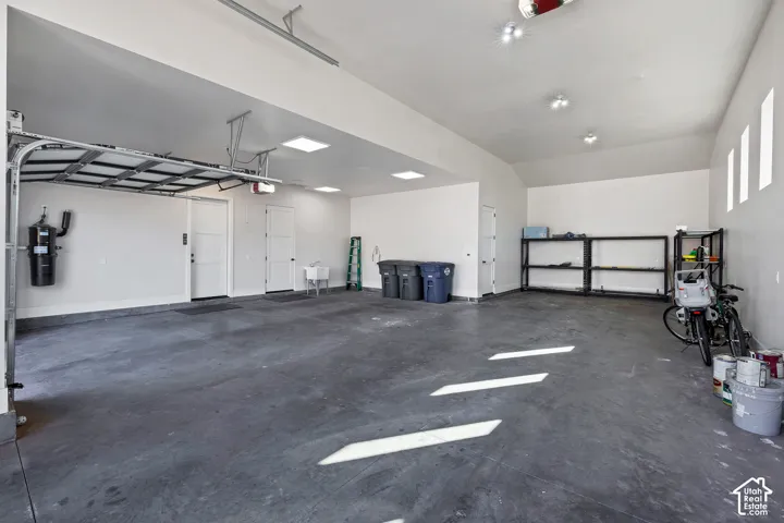 Spacious garage with multiple recessed light fixtures, built-in utility sink, and wall-mounted central vacuum system