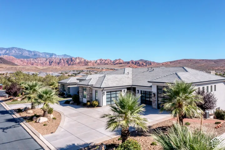 Contemporary exterior with a multi-gabled tile roof, stone accents, and expansive driveways