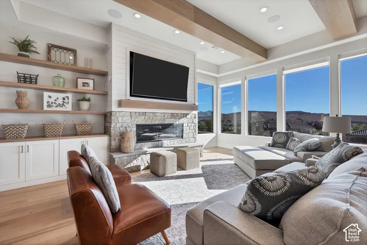 Spacious living area featuring a stone-clad fireplace, built-in shelving, expansive windows, and a coffered ceiling