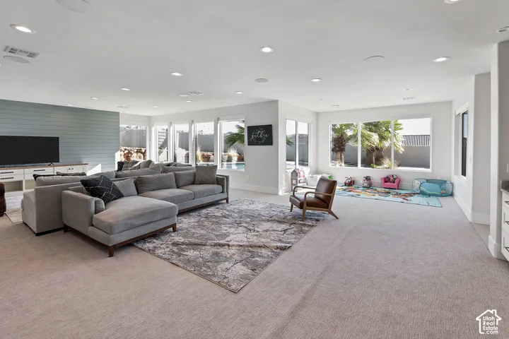 Recessed lighting, light-toned carpeting, ample natural light, shiplap accent wall, built-in cabinetry