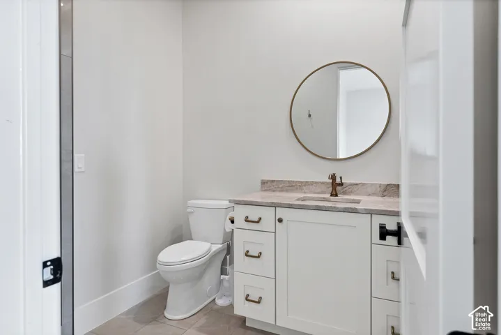 White vanity with bronze-finish hardware, light-toned countertop, and round framed mirror