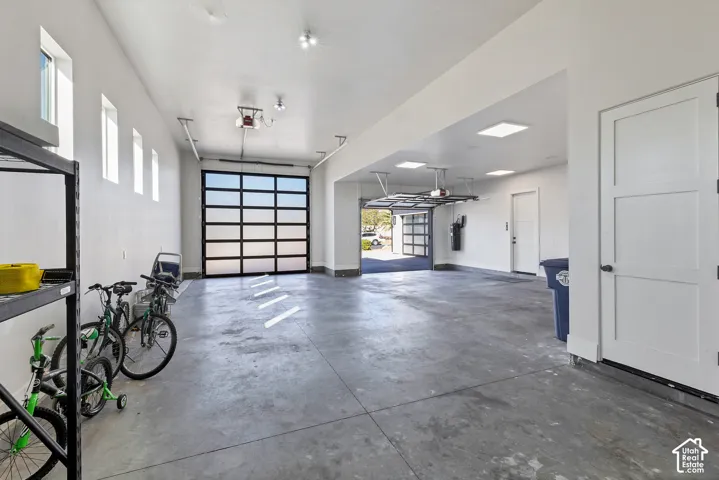 Expansive garage featuring multiple automatic glass-paneled doors, concrete flooring, and recessed lighting