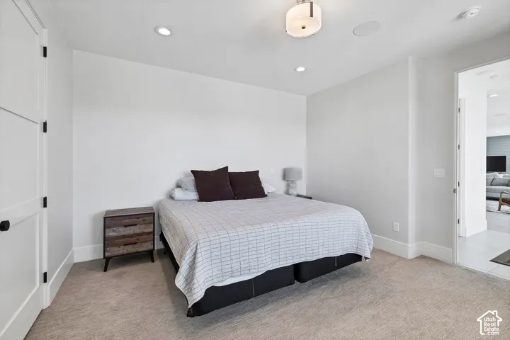 Recessed lighting, ceiling-mounted light fixture, white walls, carpet flooring, and a two-panel door with black hardware