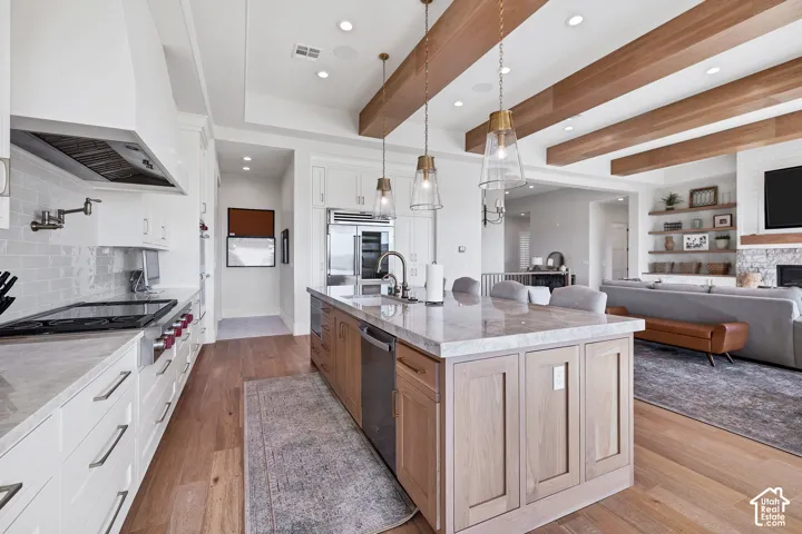 Gourmet kitchen featuring a large island with seating, stainless steel appliances, and wood-finish flooring