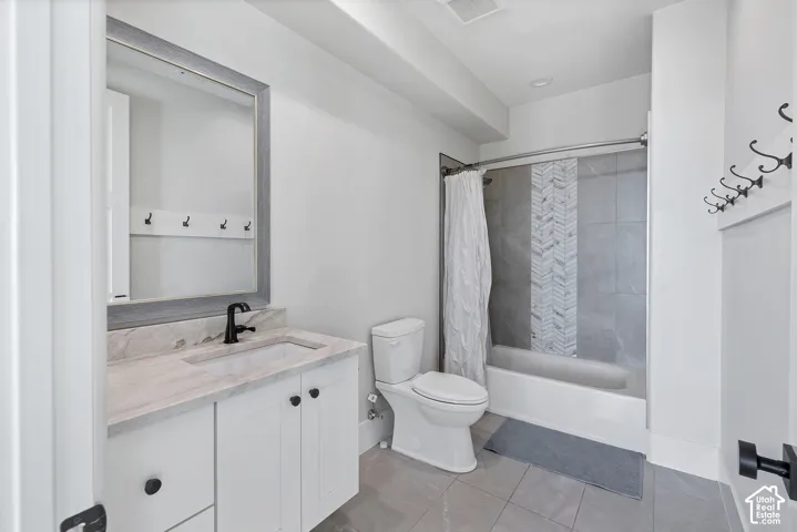 White vanity with stone countertop and integrated sink, framed mirror, matte black faucet, and white subway tile shower surround with a decorative herringbone accent